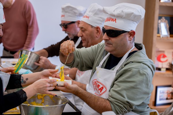 Uno de los participantes rellena el papel con la masa del sobao